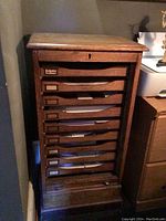 Front view of the oak organizer showing ten pull-out drawers and keyhole detail