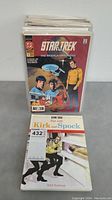 Stack of 42 Star Trek comic books with visible cover of comic #1; hardcover book titled 'Star Trek Fun with Kirk and Spock' in front of comics
