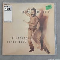 Front cover of Bobby McFerrin Spontaneous Inventions LP album showing image of McFerrin dancing shirtless on beige background with album title and artist name.