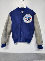 Front view of the blue wool body and gray leather sleeves jacket with Toronto Blue Jays patch on chest and snap button closure.