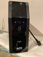 Front view of APC Back-UPS Pro 1100VA showing LCD screen, control buttons, USB port, and branding.