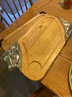 Full view of the wooden cutting board with two metal bull heads on opposite corners, showing the carved groove and circular section.