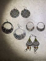 Full lot of 5 pairs of silver drop earrings laid out on fabric, showing varied designs and styles.
