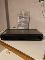 Front view of the FoodSaver vacuum sealer machine on a white surface with instruction manual behind