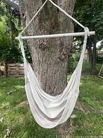Full view of the hanging seat swing showing the fabric and wooden bar suspended from a tree.
