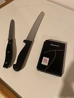 Two knives and a closed compact digital kitchen scale with brand label Starfrit visible.