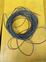 Full view of coiled wire clothesline laid on a yellow surface.