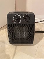 Front view showing the two control knobs and mesh grille of the compact black space heater