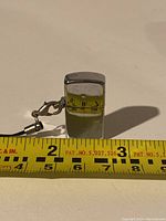 Tiny silver-colored lighter next to measuring tape showing height of about 1 inch
