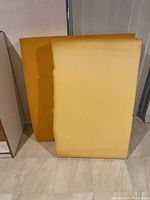 Two large rectangular yellow foam pieces leaned against a wall, showing size and color.