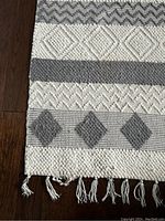 Close-up image of corner of the rug showing geometric pattern and fringe with damage