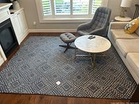 Full view of blue area rug under coffee table, armchair, and sofa showing overall size and condition in a living room setting.
