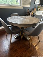 Assembled view of round table with six grey upholstered chairs in dining area