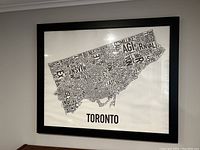 Framed black and white typographic Toronto map print on wall, showing clean and intact frame and artwork.