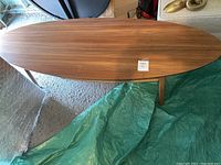 Top view of the oval wooden coffee table showing wood grain and scratches.