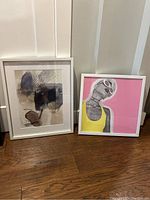 Two framed art prints together: an abstract watercolor in white frame and a stylized colorful portrait of a woman also in white frame