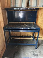Full view of the Mastercraft tool bench showing frame, pegboard back, main work surface with paint stains, and bottom shelf.