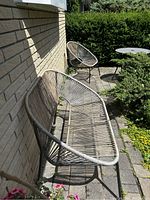 2-seater bench and 1-seater chair on outdoor patio against brick wall with plants around