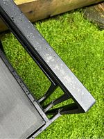 Close-up of the black metal frame of one chair showing weathering and water spots.