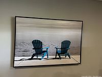 Framed photograph depicting two Adirondack chairs on a dock over water, captured with balanced lighting and neutral tones.