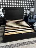 Full queen bed frame showing wooden slats and dark brown finish with headboard and footboard.