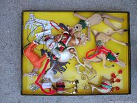 A box of assorted Christmas ornaments of various shapes and sizes including Santa Claus figures, wooden reindeer, snowman, star shapes, and a wooden artist doll.
