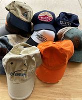 Photo of nine baseball caps arranged on a wooden surface showing various colors and logos.