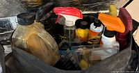 Photo of used car maintenance supplies in a black Ford Escape bag showing various spray bottles, oil, and small bottles.