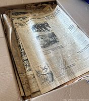 Box of vintage newspapers from 1939 showing aged and yellowed pages with text and photographs.