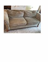 Green two-seat sofa with two back and two seat cushions on a patterned rug.