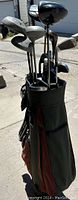 Image showing full golf club set in the golf bag outdoors, highlighting the club heads with metal shafts.