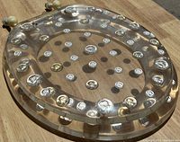 Top-down view of acrylic toilet seat lid with embedded coins on a wooden surface