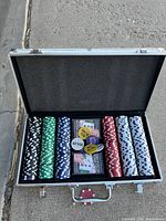 Open poker chip case with poker chips arranged by color, two decks of cards and two dealer buttons.