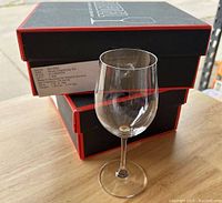 Single Vinum Chardonnay white wine glass in front of stacked Riedel boxes.