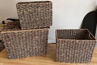 Three stacked water hyacinth storage baskets in varying sizes with tight woven natural fiber construction and one separate smaller bin.