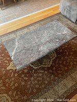 Rectangular marble coffee table top and base on patterned rug