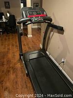Full view of black Livestrong treadmill showing belt, side rails, and base with brand name.