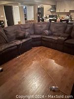 Full view of L-shaped brown fabric sectional sofa in room with wooden floor, showing multiple seating and armrests.