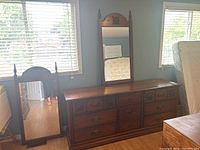 Photo showing the wood veneer dresser with nine drawers and two mirrors behind it, positioned near a window with blinds.