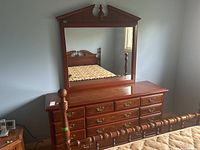 Front view of wood veneer dresser with attached mirror and seven drawers with metal pulls