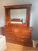 Front view of wood veneer dresser and mirrored hutch with visible chest drawers and side shelves.
