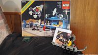 Photo of Lego set 6970 box and assembled components including mini-figures and building with equipment and satellite dishes.