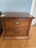 Front view of wood veneer night table with 2 drawers and metal handles, showing design, condition and style.