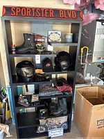 Overview of black shelving unit with various Harley Davidson branded items including boots, helmets, signs, mugs and apparel