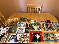 Overview of 17 decorative hot plates and coasters arranged on a wooden table showing a variety of animal and nature themes