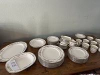 Full set displayed on wooden table: stacks of plates, cups, saucers and serving pieces
