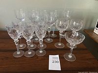 Full lot of 13 crystal glasses of different types arranged on a wooden surface.