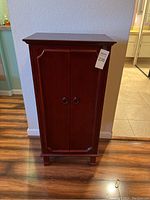 Closed view of the stand-up wooden jewelry box cabinet with two front doors and tag number 235 attached.