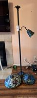 Full view of floor lamp with one small attached Tiffany style shade and two extra large Tiffany style lamp shades placed on floor.