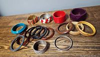 Photo showing a variety of bangle bracelets in wood, plastic, and metal materials including blue, red, purple, and silver tones.
